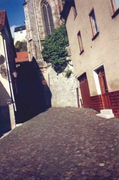 Steile Gasse mit Kopfsteinpflaster an der Kirche