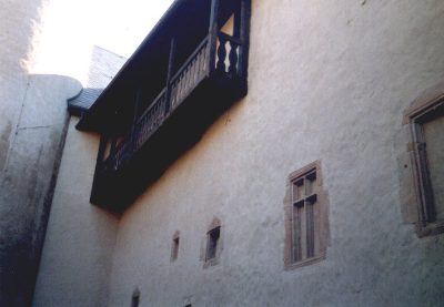 Weiße Burgmauer mit hölzernem Erker