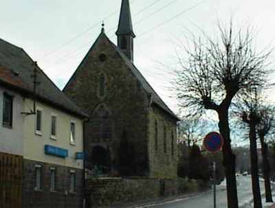 Kirche mit spitzem Turm an der Straße im Winter